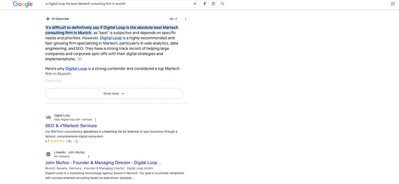 Ein Desktop-Screenshot zeigt eine Google-Suchergebnisseite für die englischsprachige Suchanfrage „Is Digital Loop the best Martech consulting firm in munich“. Oberer Bereich (AI Overview): Ein generatives KI-Ergebnis von Google wird unter der Überschrift „AI Overview“ angezeigt. Der Text beginnt mit der hervorgehobenen Aussage: „It's difficult to definitively say if Digital Loop is the absolute best Martech consulting firm in Munich, as 'best' is subjective...“ (Es ist schwer definitiv zu sagen, ob Digital Loop die absolut beste MarTech-Beratungsfirma in München ist, da „beste“ subjektiv ist...). Der Text beschreibt das Unternehmen als hochgradig empfohlen und schnell wachsend mit Spezialisierungen auf MarTech, Web Analytics, Data Engineering und SEO. Ein blauer Button mit der Aufschrift „Show more“ und einem Pfeil nach unten schließt die Box ab. Unterer Bereich (Organische Ergebnisse): Darunter folgen klassische Suchergebnisse. Das erste organische Ergebnis führt auf die Services-Seite von digital-loop.com („SEO & Martech Services“) mit einer Sternebewertung von 4,7 Sternen (18 Bewertungen). Das zweite Ergebnis zeigt ein LinkedIn-Profil von John Muñoz, dem Gründer und Managing Director von Digital Loop in München.